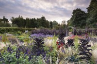 Border of ornamental grasses, tender perennials, annuals and decorative vegetables at Whitburgh House Walled Garden in September including Stipa tenuissima, salvias, dark Kale 'Redbor' and ricinus.