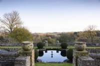 Rectangular lily pond on the Jewson Terrace at Cotswold Farm Gardens in February framed by clipped yew.