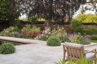 Sandstone terrace with seating, pool and border of David Austin Roses and Pittosporum topiary balls.