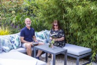 Garden owners sitting on sofa next to large bamboo plants