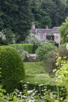 View across garden to house at Moor Wood, Gloucestershre, with rambling roses, and clipped hedges