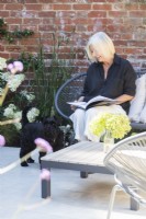 Garden owner sitting down with dog while reading