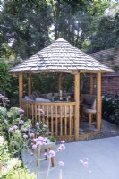 Round wooden gazebo with tile roof and seating inside