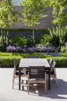 Grey outdoor dining table and chairs on paved contemporary terrace