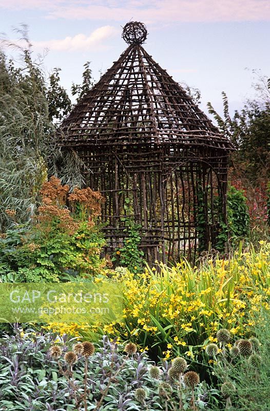 A rustic, woven twig summer house in early autumn
