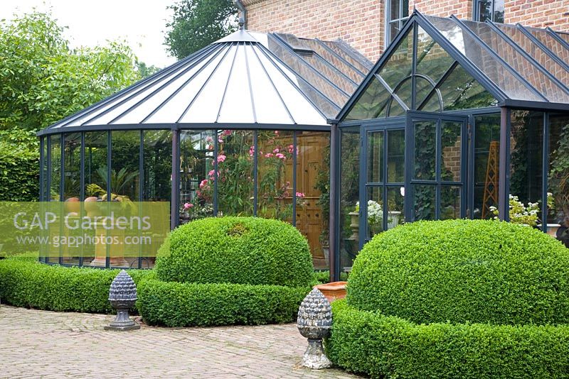 Winter garden conseravtories with clipped Buxus hedging and stone ornaments outside