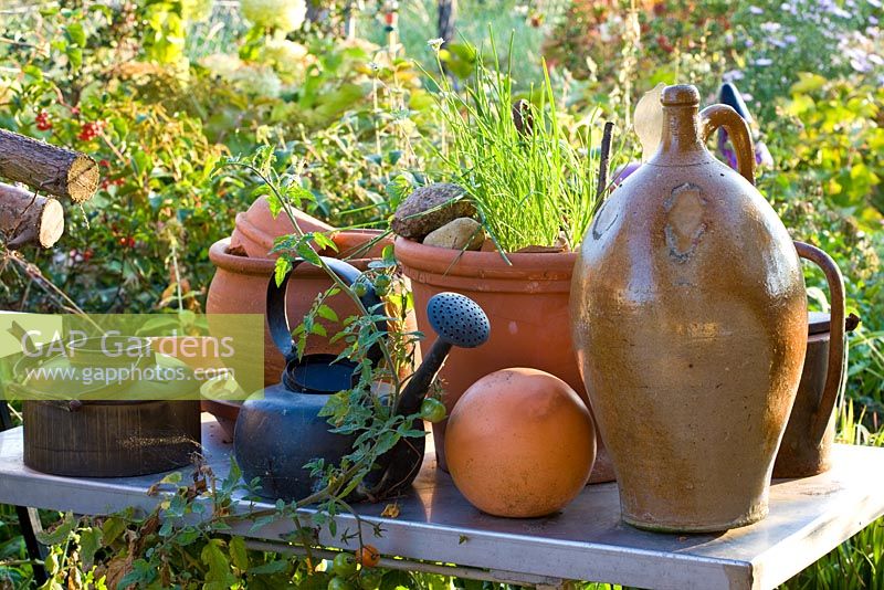 An arrangement of clay pots, a jar, a ball and tea kettles on a metal table