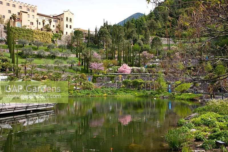 A lake reflects the scenery at The Botanical gardens of Trauttmansdorff Castle in Merano, Italy