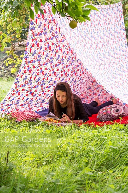 Young girl reading a book inside a tent