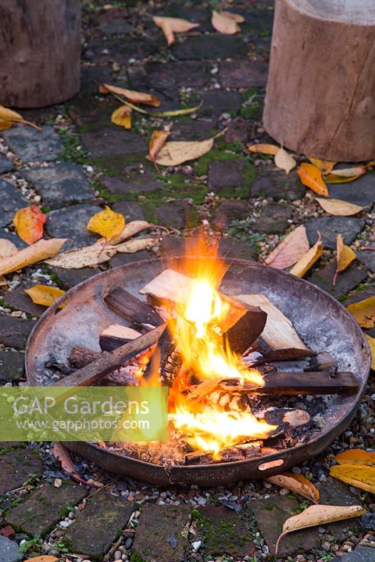 A firepit alight in an autumnal back garden