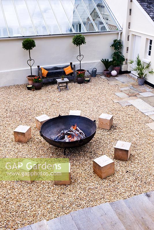 Gravel seating area with large square wooden blocks for seats and fire cauldron