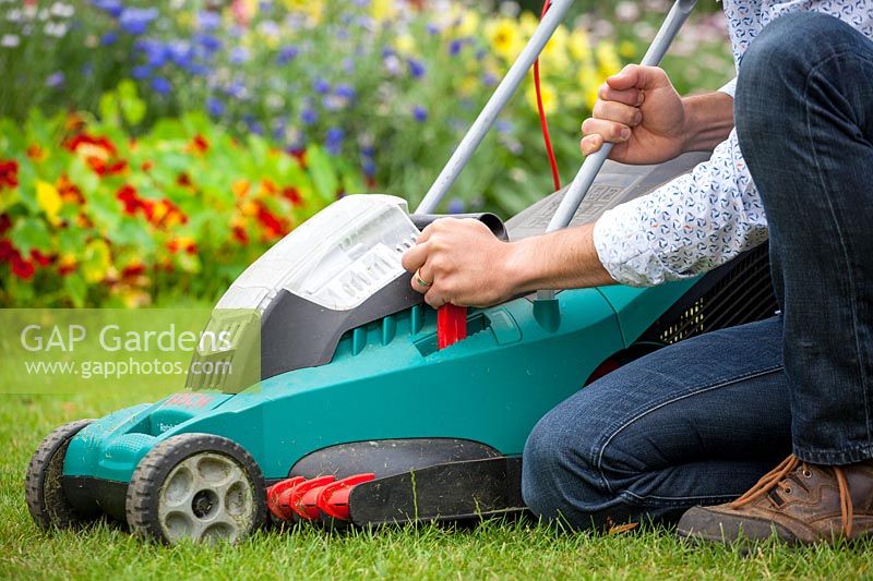 Raising the height of blades on a rechargeable electric lawnmower. July