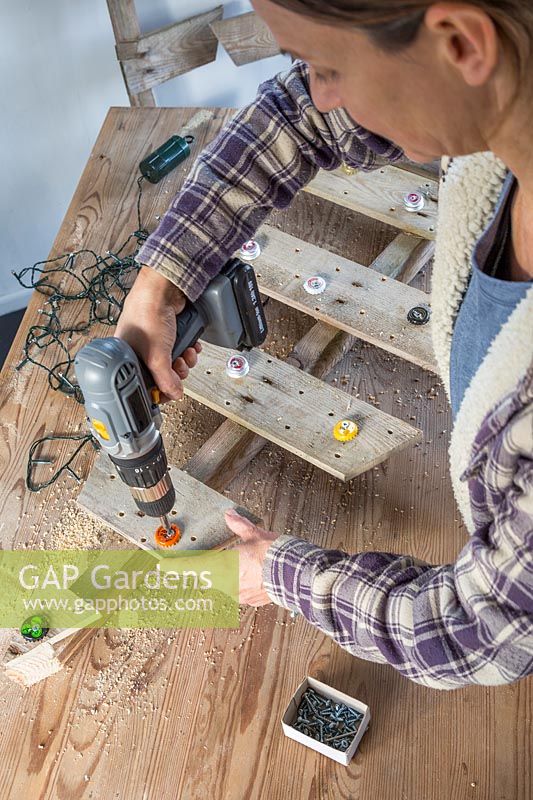 Attaching bottle caps to pallet tree with cordless screwdriver