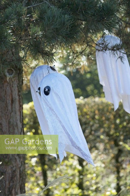 Flying halloween ghosts decorations hanging in trees.