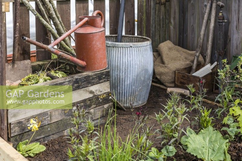 Small wooden compost bin, watering can and water barrel in vintage style