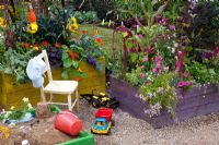 Children's garden with sandpit and vegetables growing in raised bed