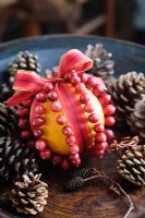 Making a Cranberry and Orange pomander for Christmas - finished pomander in a dark wood bowl with pine cones