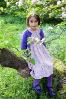 Young girl sitting on tree trunk with Apple blossom