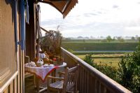 A table is prepared on the wooden balcony with white dishes and Autumn fruit and the view is on the Elbe, Germany