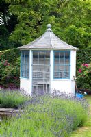 Blue and white summerhouse. Lavandula - Lavender and watering can