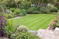 Flowerbeds and paving surrounding lawn 