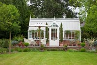 Garden furniture, parasol and terracotta pots in front of victorian style conservatory with brick stone terrace, with  Cupressus sempervirens 'Stricta - Germany