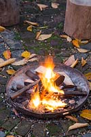 A firepit alight in an autumnal back garden