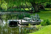 Decked terrace beside the lake with adirondack wooden chairs and boat