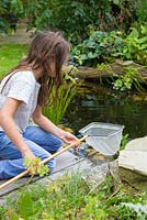 Young girl pond dipping in her garden. Checking net
