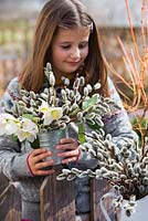 Girl with arrangements of Christmas roses and catkins.
