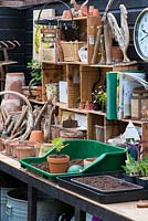 A potting bench with tools, pots and propagation equipment.