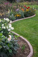 Sawtooth style brick edging containing a border of mixed Dahlias and Heleniums