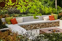 Firewood storage bench seating, Corten steel fire pit and mixed planting - Graduate Gardeners 'Sunken Retreat' Garden - RHS Malvern Spring Show 2016. Designer: Ann Walker