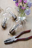 Making hanging flower vases from lightbulbs. Remove the small silver end cover with tweezers of pliers, this should just pull off.