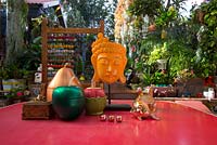 Eclectic ornaments on a red retro laminex table in covered outdoor entertaining area with Thai style mask, June.