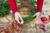 Using green florist wire to secure Yew foliage onto a natural wreath base