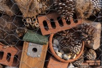 Looking at a section of a bug hotel, with old bricks, fir cones, bird box, bamboo canes and coconut matting encased with wire netting.