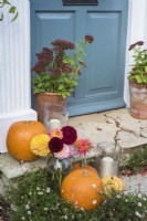 Front door and stone steps decorated for Halloween with pots of Sedums, squashes, flowers and candles 