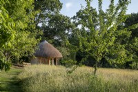 The Orchard Shelter at Rosemoor Gardens, RHS, Devon, a thatched traditional barn style building overlooking the apple orchards.