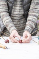 Woman poking the sticks into the holes in the conkers