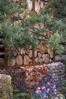 Boundary log wall with gabions filled with broken pots, stones and gathered leaves