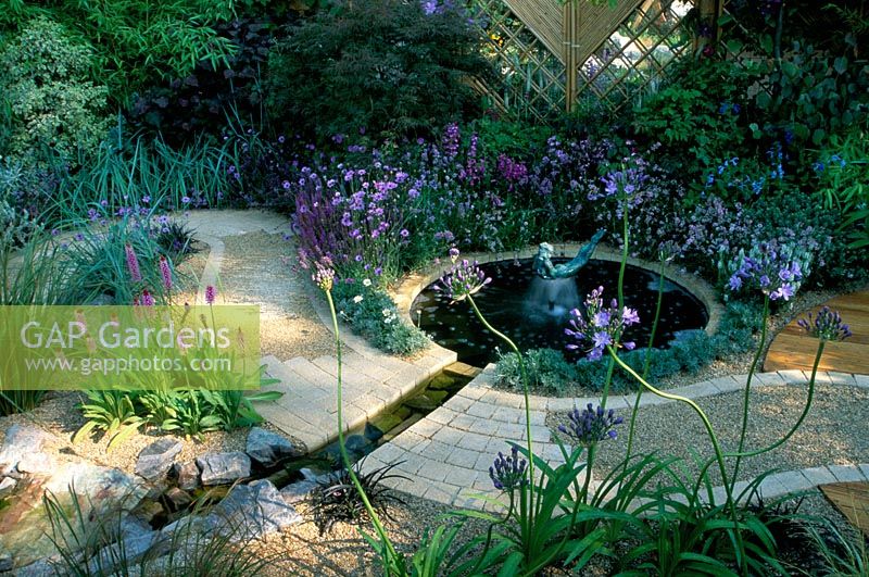 Feng shui garden with water rill and circular pond. Curved path and mirror, planting in cool colours