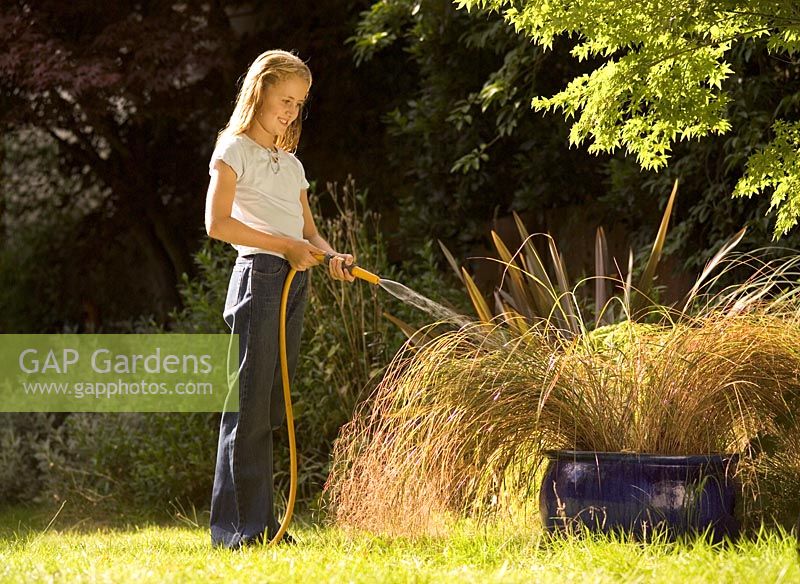 Girl watering plants with hosepipe