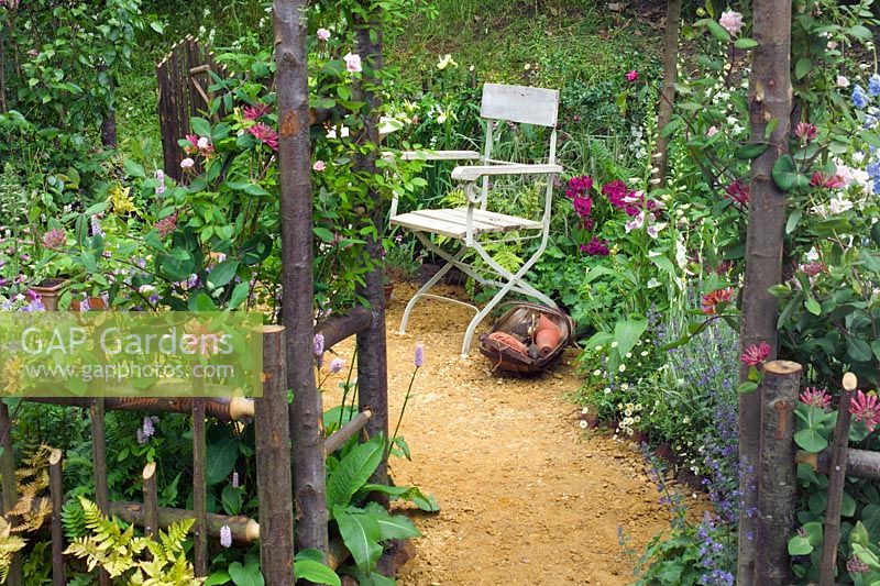 View to chair through arch in cottage garden. 'Fittleworth' by Fittleworth Horticultural Society. Chelsea FS 2005