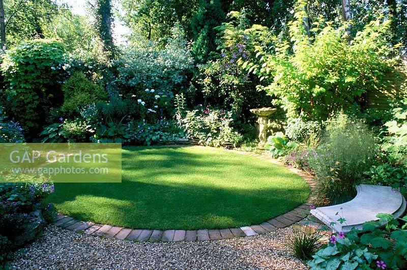 Shady garden with circular lawn, mixed planting and seating. Ladywood in Hants 