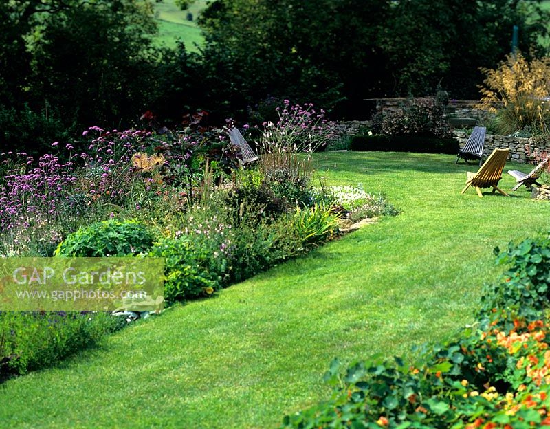 Informal country garden with mmixed borders,lawn and wooden seats