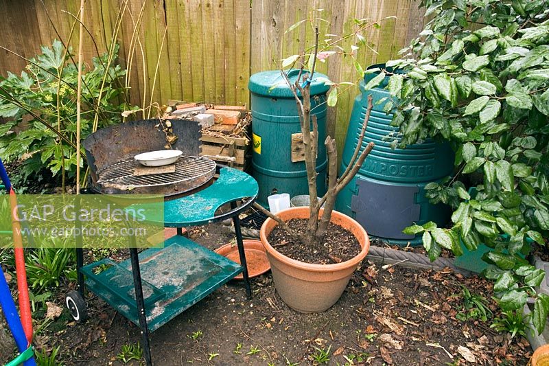 Untidy garden with pots, barbecue and compost 