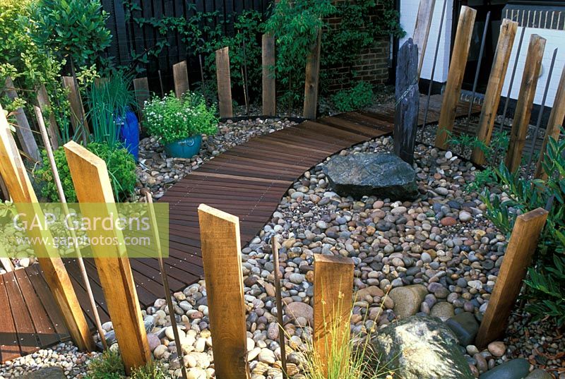 'Zen Seashore Garden' - Small, low maintenance pebble garden with stone boulders, winding wooden path, and wooden and metal post fence.