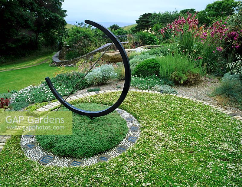 A dry, coastal and windy garden with a sun dial positioned within a circle of Thymus in July.