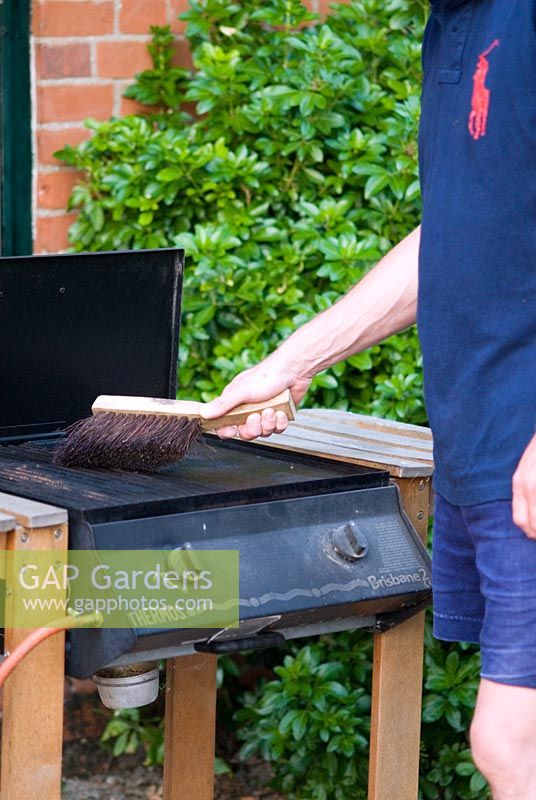 Man cleaning a Barbecue with a wire brush